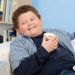 Boy lies on the sofa and eats donuts